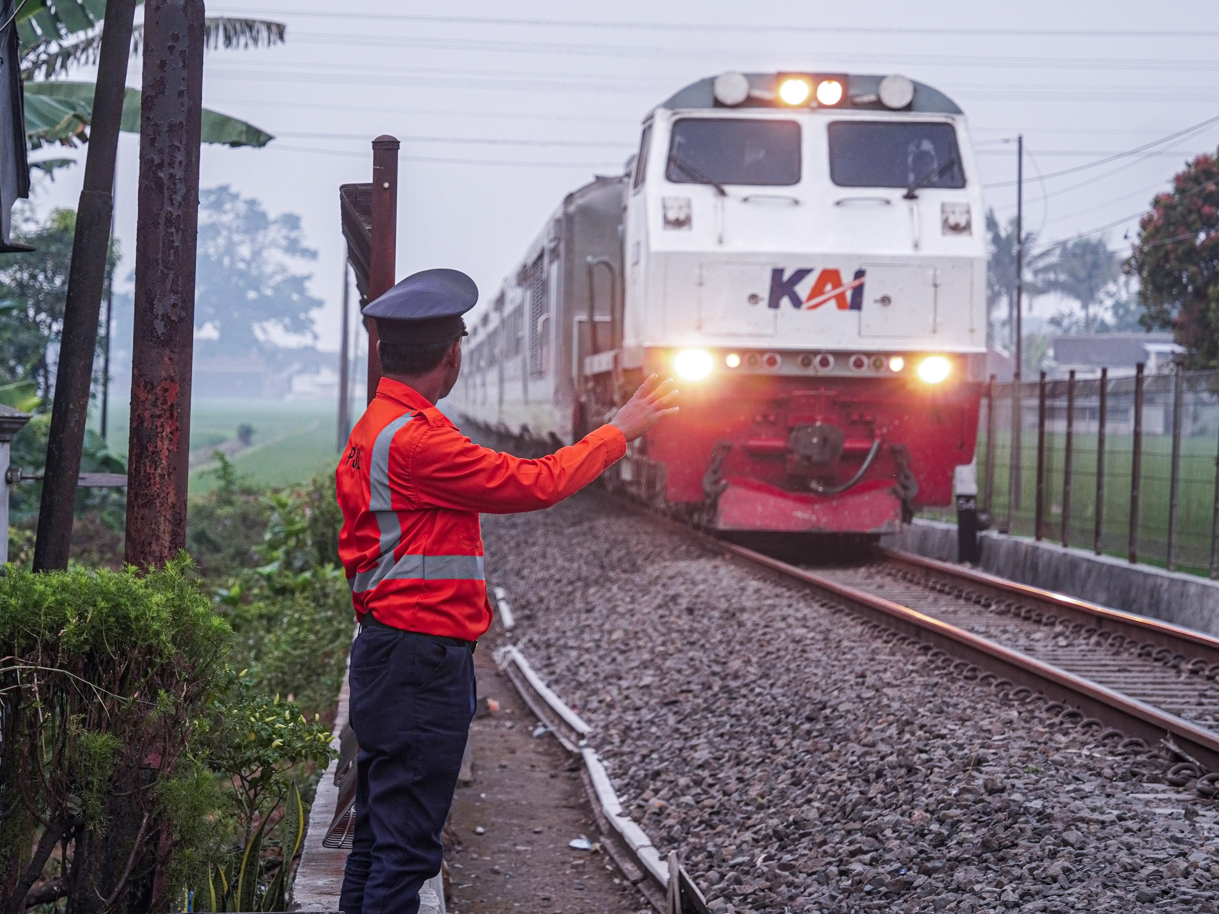 Kereta api Majapahit yang melintas langsung di perlintasan kereta api dengan petugas PJL yang menyapa dengan melambaikan tangan